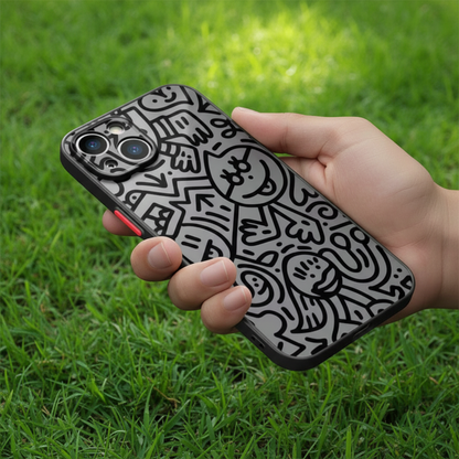 Hand holding a phone with a black and white patterned case on grass